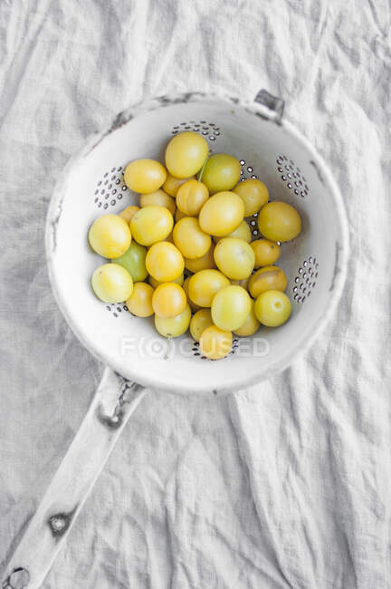 Yellow wild plums in vintage metal colander — Stock Photo