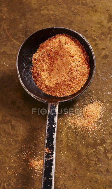 Crumbs and spices in spoon on rustic surface — Stock Photo
