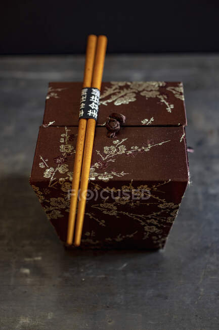 Boîte de soie orientale avec baguettes sur la surface de la pierre — Photo de stock