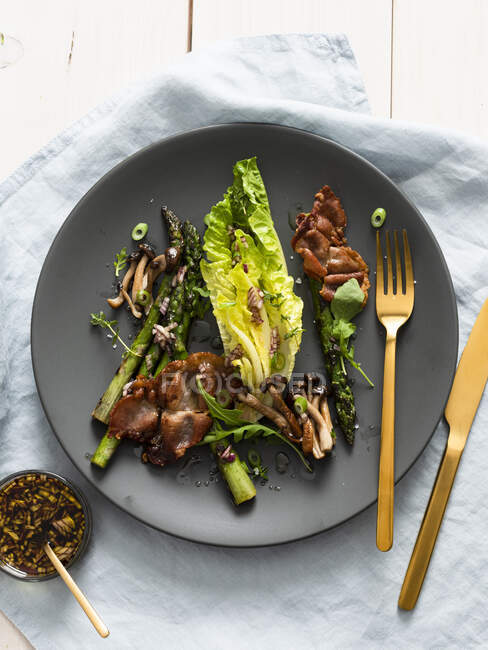Lettuce with grilled asparagus, mushrooms and serrano ham — Stock Photo