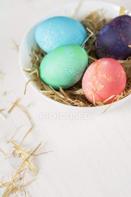 Easter eggs in nest on wooden background — Stock Photo