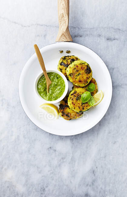 Millet patties with kale and zucchini, served with spinach pesto and lemon vedges — Stock Photo