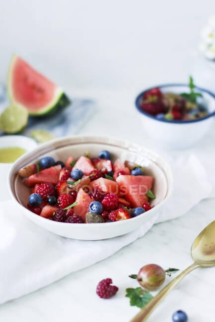 Summer fruit salad with berries and watermelon in bowl on table — Stock Photo