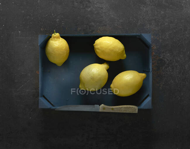 Vier Zitronen in einer Holzkiste — Stockfoto