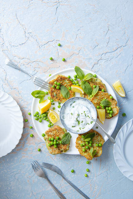 Courgette and pea fritters with lemon and minted yoghurt dip - foto de stock