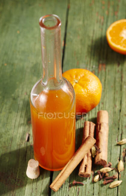 Xarope de especiarias de tangerina caseiro com canela em garrafa e ingredientes na mesa — Fotografia de Stock