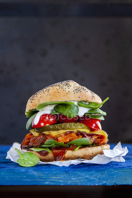 Un hamburger avec une galette de citrouille, tomates cerises et cornichons — Photo de stock