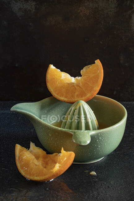 Rebanadas de naranja exprimida y exprimidor de cerámica - foto de stock
