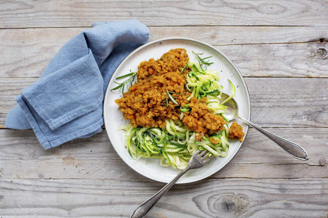 Courgettes noodles with lentil Bolognese, fork and spoon on plate — Stock Photo