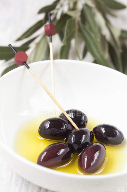 Чорні оливки каламата в мисках з дерев'яними шампурами — стокове фото