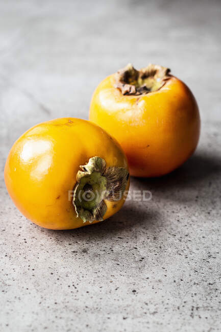 Deux fruits frais de sharon sur la surface du béton — Photo de stock