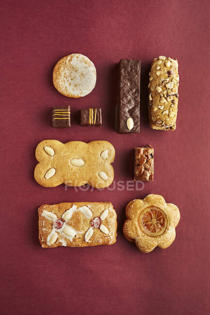 Vari biscotti di pan di zenzero su carta rossa, vista dall'alto — Foto stock