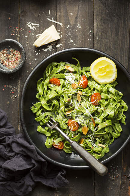 Spinach pasta with cooked cherry tomotoes, parmesan and almonds in a lemon and olive oil dressing — Stock Photo