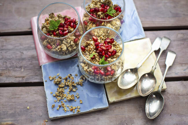 Granola with yoghurt and pomegranate seeds in glasses — Stock Photo