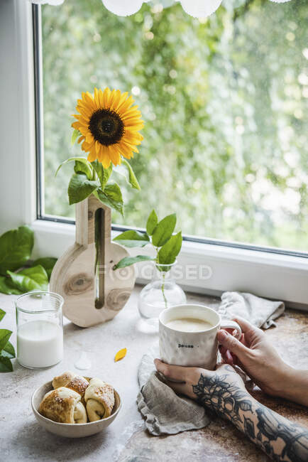 Una pausa para el café cerca de una ventana con leche, café y croissants - foto de stock