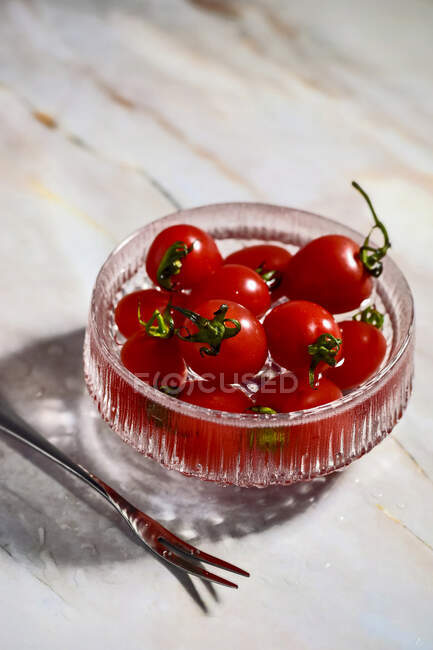 Tomates en un tazón de vidrio - foto de stock