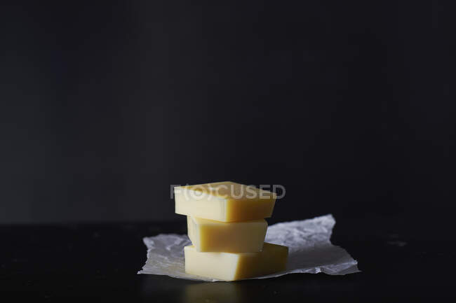 Pila de tres rebanadas de queso Emmental sobre una hoja de papel - foto de stock