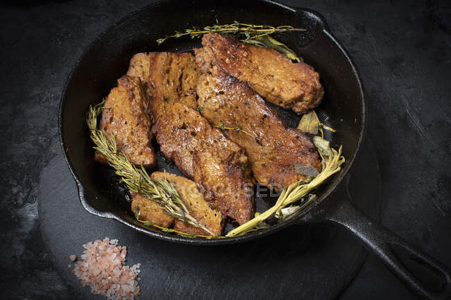Roasted seitan in cast iron pan with various herbs and spices — Stock Photo