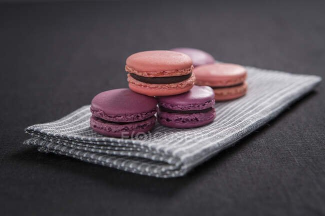 Purple and pink macarons on striped cloth napkin — Stock Photo