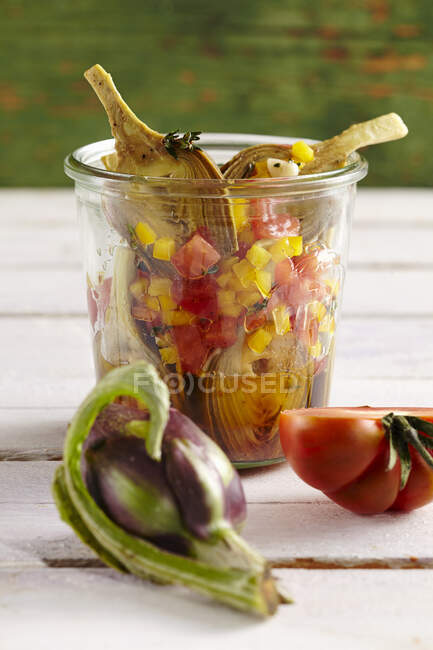 Young pickled artichokes with tomatoes, peppers, vinegar, oil, lemon, white wine and spices — Stock Photo