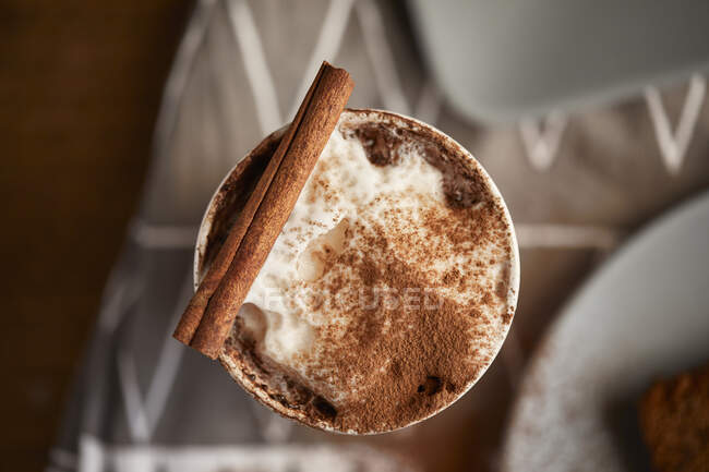 Cappuccino with cocoa and cinnamon stick — Stock Photo