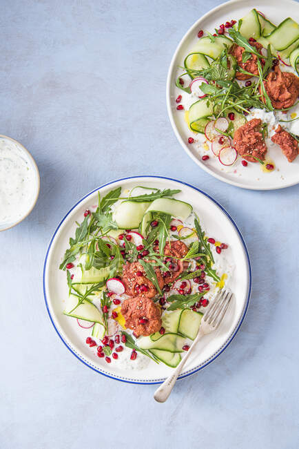 Beetroot baked falafels with coriander yoghurt, cucumber ribons, pomegranate and rocket salad. — Stock Photo
