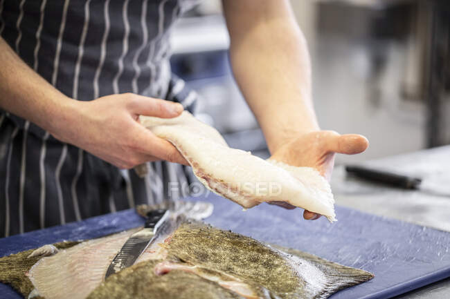 Обрезанный снимок шеф-повара, готовящего сырую рыбу для приготовления пищи — стоковое фото