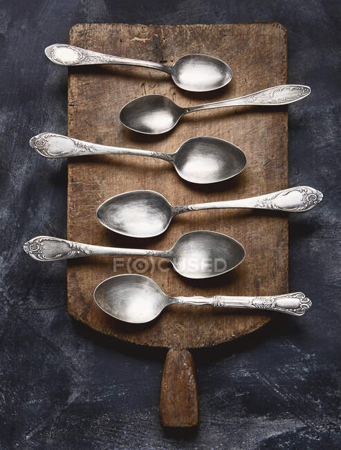 Chopping board with spoons on black background — Stock Photo