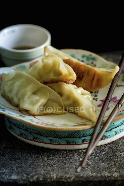 Dumplings con salsa de soja y palillos en el plato - foto de stock