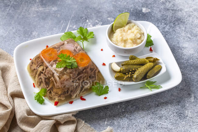 Aspik mit eingelegter Gurke und Meerrettichsoße. Kholodets ist ein geliertes Fleischgericht der traditionellen Küche. — Stockfoto