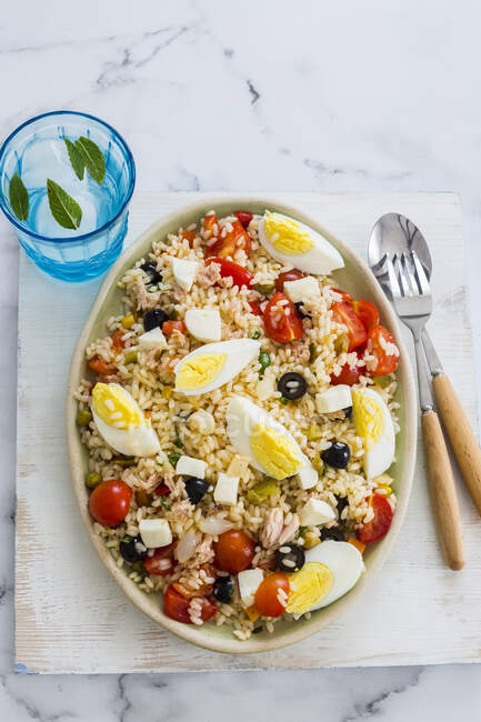 Italian rice salad with eggs and tuna served on table with drink — Stock Photo