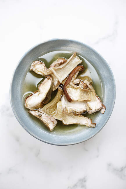 Dried porcini mushrooms in bowl of water — Stock Photo
