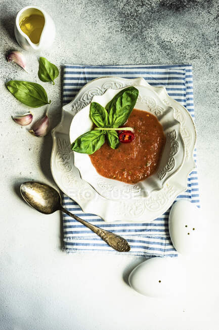Zuppa di pomodoro tradizionale spagnolo Gazpacho servito in ciotola di ceramica con foglie di basilico fresco su sfondo di pietra con spazio copia — Foto stock