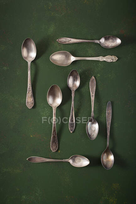 Various vintage teaspoons on green surface — Stock Photo