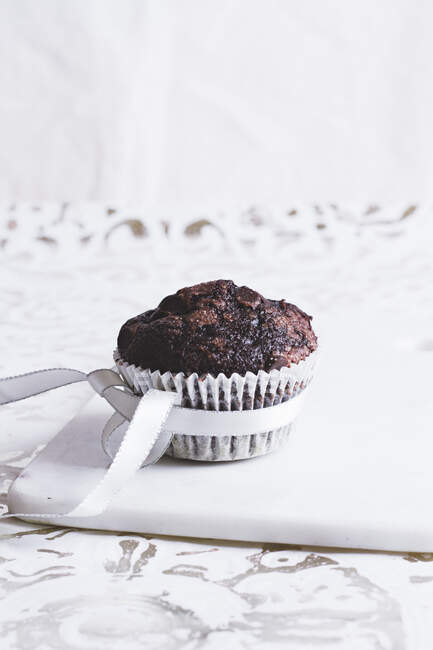 Ein Schokoladen-Muffin in einem Papierkuchen mit Schleife — Stockfoto