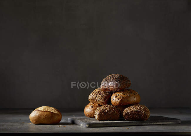 Різні хлібні рулони на фоні темної стіни — стокове фото