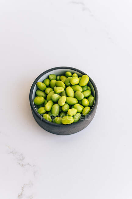 Pois verts dans un bol sur fond blanc — Photo de stock