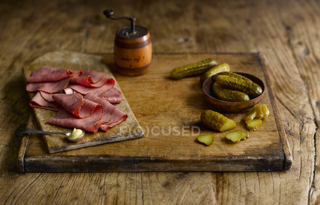 Pastrami and pickles on wooden cutting board — Stock Photo