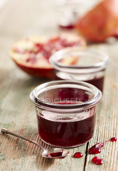 Fresh pomegranate jam in glass jar on wooden table — Stock Photo