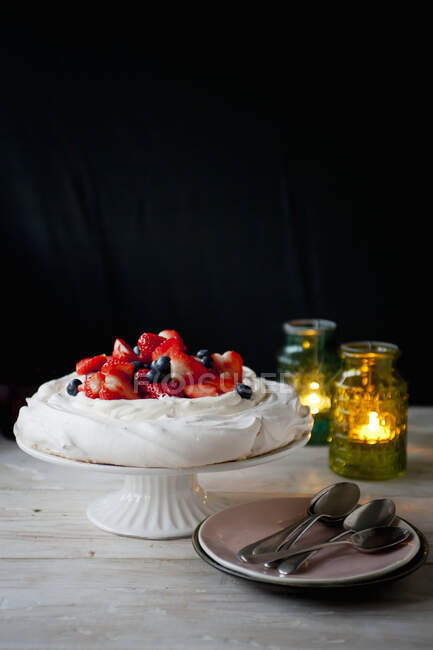 Pavlova with fresh strawberries and blueberries served on stand — Stock Photo
