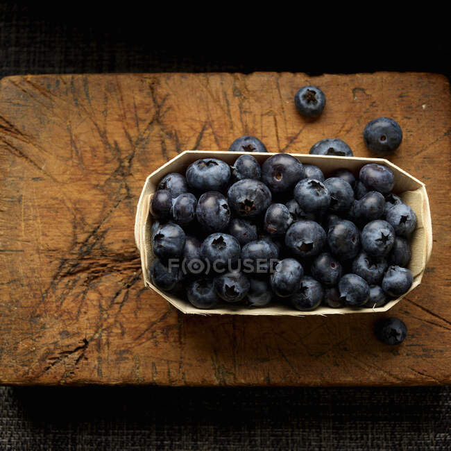 Blueberries in wooden tray on cutting board — Stock Photo