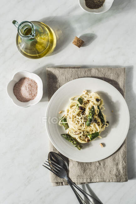 Espaguetis con espárragos, queso crema y salsa de limón, semillas de calabaza, cebolla y aceite de oliva - foto de stock