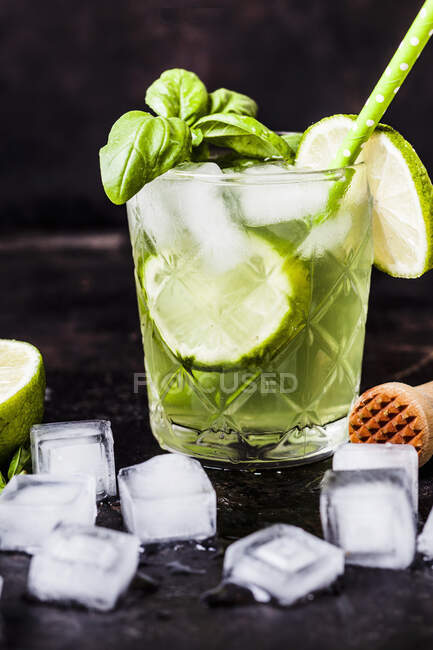 Gin basil smash cocktail with lime slices and ice cubes — Stock Photo