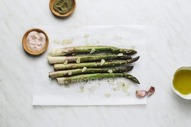 Roasted asparagus with garlic on baking paper — Stock Photo