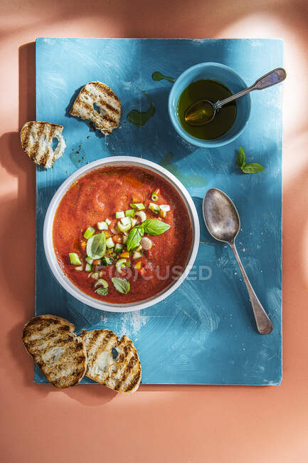 Sopa de gaspacho fria com manjericão e óleo de azeitona, pão em um lado. — Fotografia de Stock