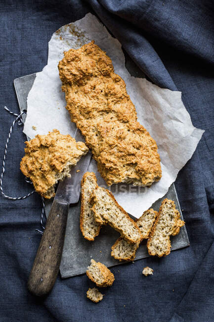 Rye and chia baguette sliced with knife on paper and board — Stock Photo