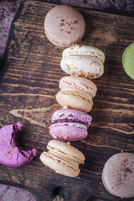 Colorful macarons on rustic wooden surface, top view — Stock Photo