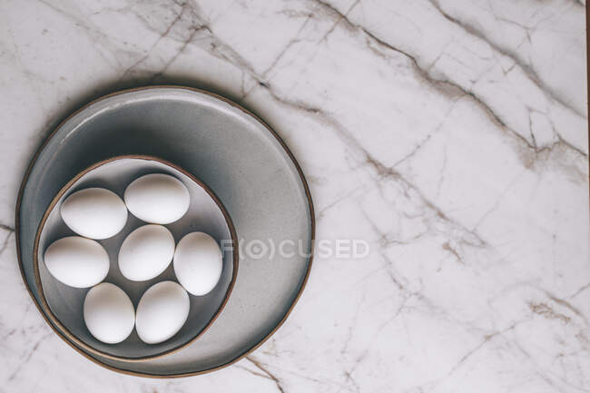 Uova bianche in ciotola su marmo — Foto stock