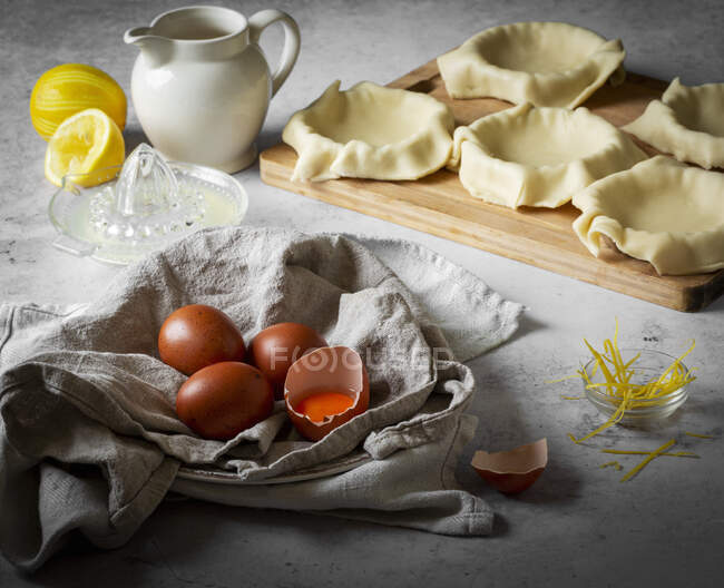 Pastry tart cases uncooked with brown eggs and lemon — Stock Photo
