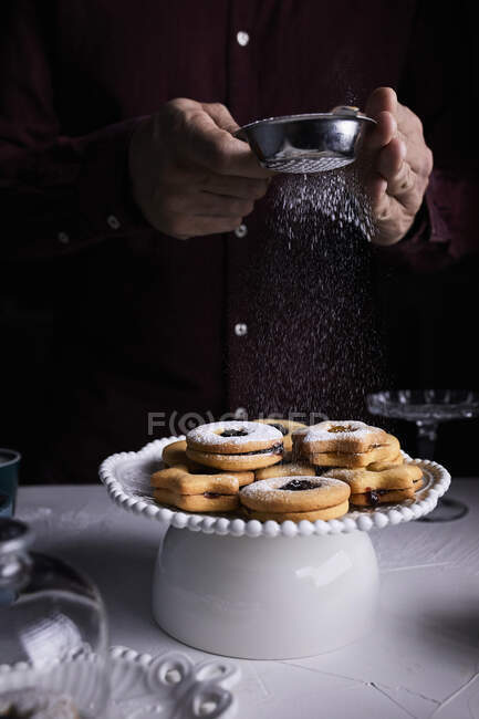 Dusting Linzer cookies with powder sugar — Stock Photo